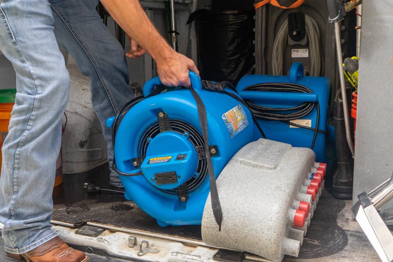 technician grabbing high powered fan from van