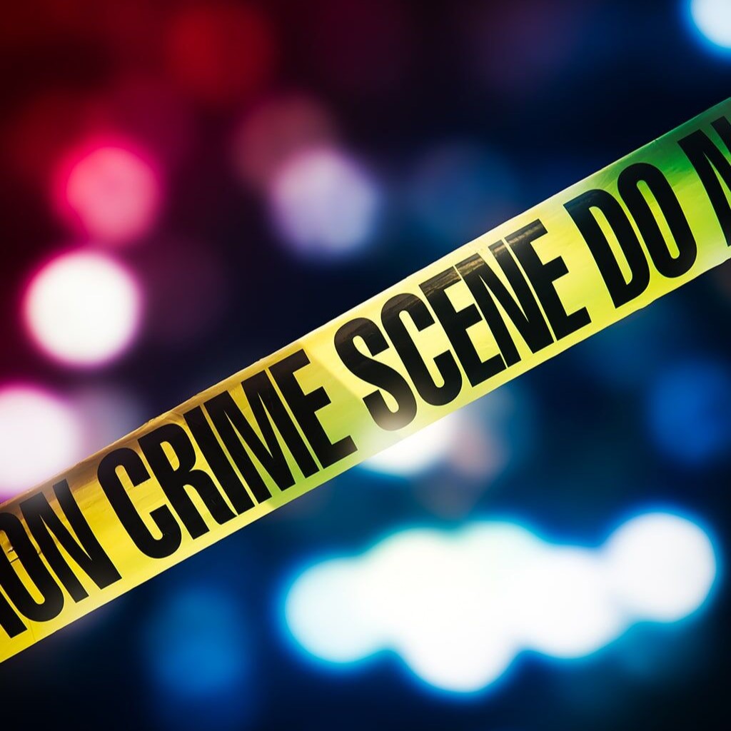 photo of crime scene tape with emergency vehicle lights in background